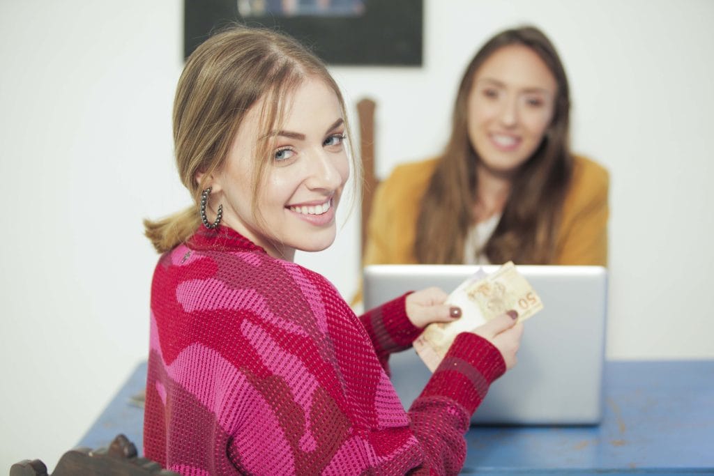 Curadoria Daz Roupaz com a cliente recebendo o pagamento pelas peças aprovadas