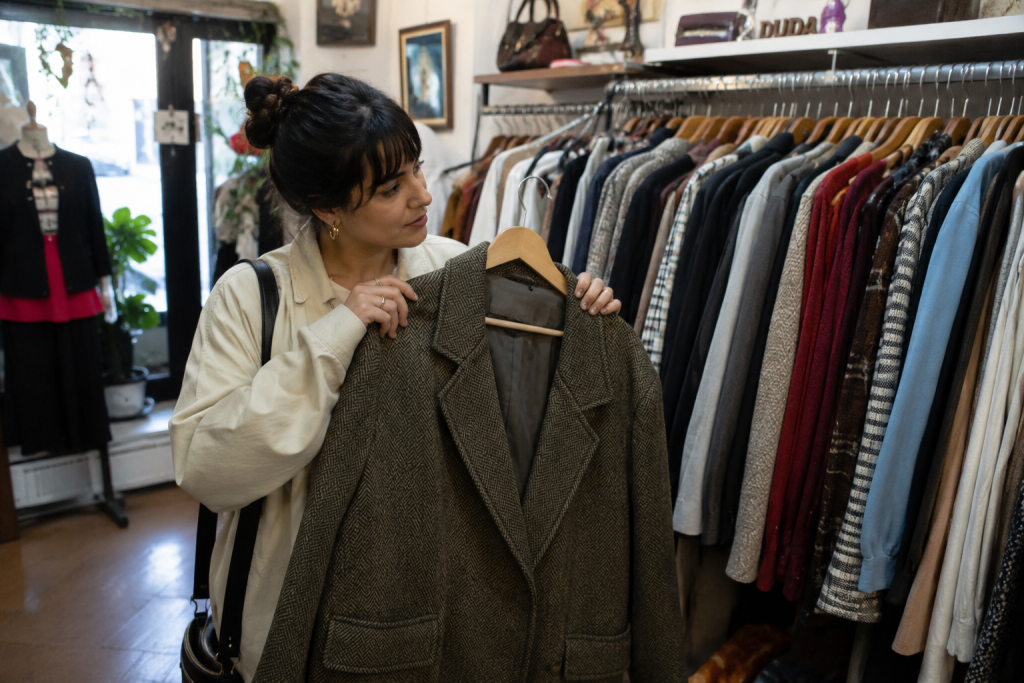 Mulher decidindo vender roupa de inverno em um brechó em SP especializado em moda circular.